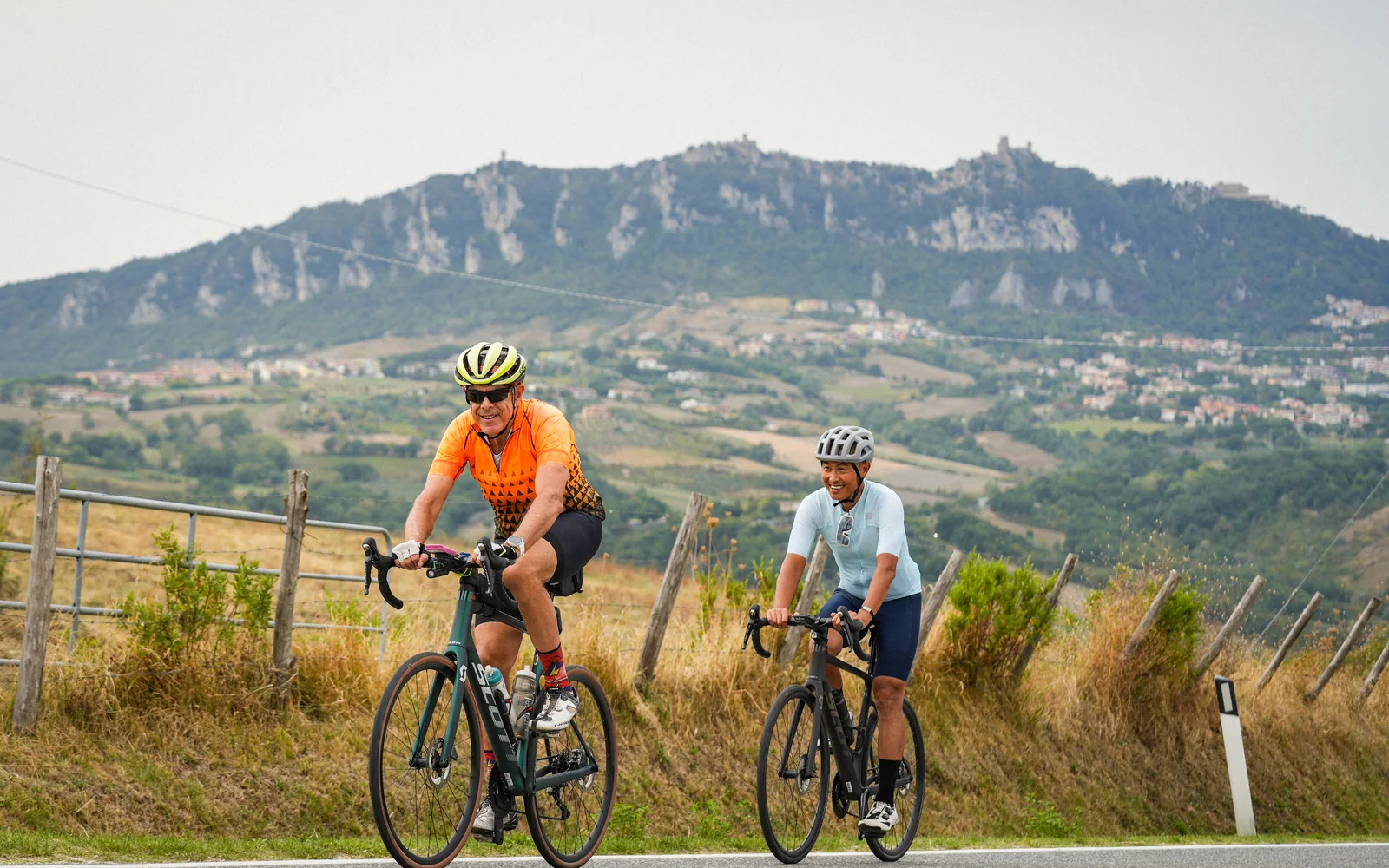 Due ciclisti in sella a bici da corsa Scott a noleggio lungo la strada per San Marino