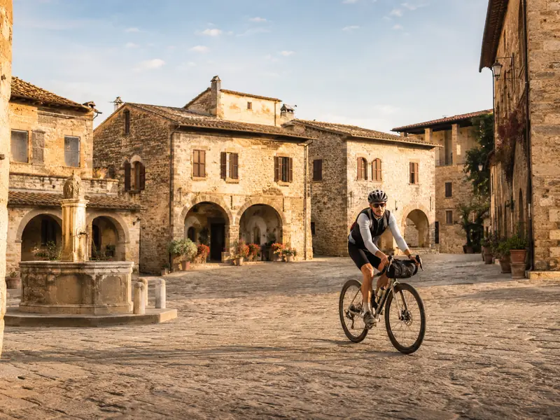 Ciclista nella piazza acciottolata di un borgo della Valmarecchia