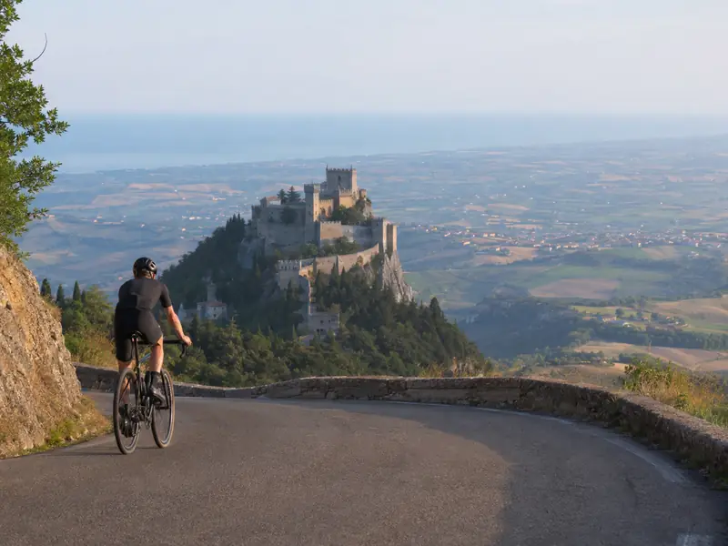 Ciclista in salita verso San Marino con vista sul mare