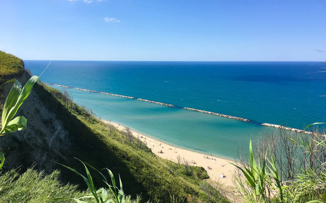 Le falesie del Monte San Bartolo a picco sulla spiaggia, con le scogliere frangiflutti e il mare Adriatico visti dall'alto